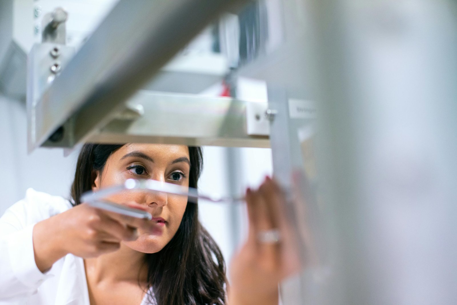 Female engineer focused on equipment in a modern lab, showcasing technology and expertise.