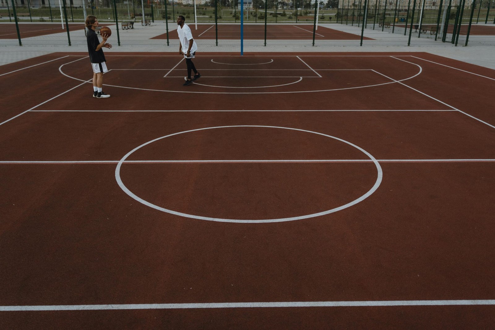 Two men playing basketball on a vibrant outdoor court during the day.